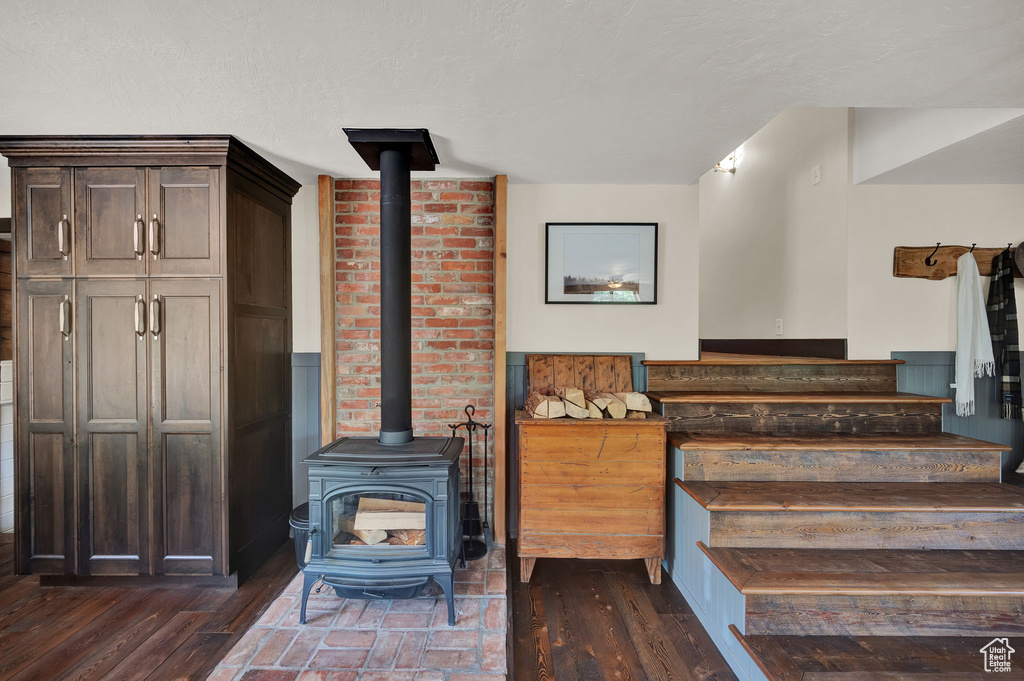 Staircase featuring brick wall, dark hardwood / wood-style flooring, and a wood stove