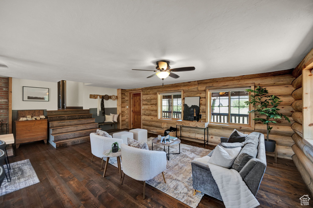 Living room with ceiling fan, log walls, and wood-type flooring