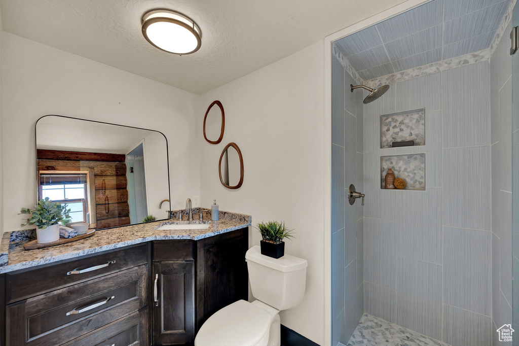 Bathroom with tiled shower, oversized vanity, and toilet