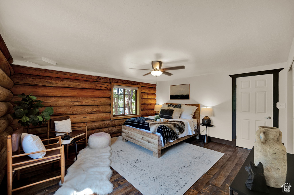 Bedroom featuring rustic walls, dark hardwood / wood-style floors, and ceiling fan