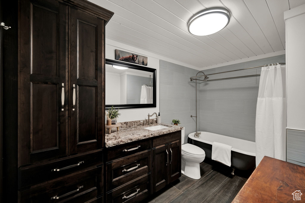 Full bathroom featuring wooden ceiling, large vanity, shower / tub combo with curtain, and toilet