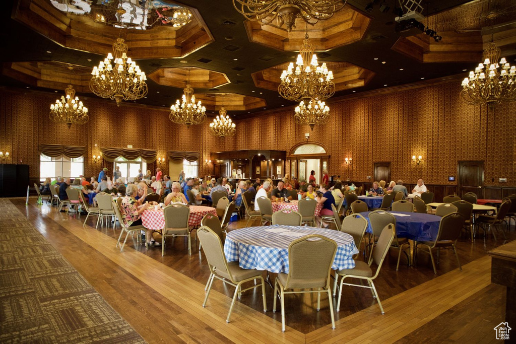 Dining space featuring a chandelier, coffered ceiling, wood-type flooring, and a high ceiling