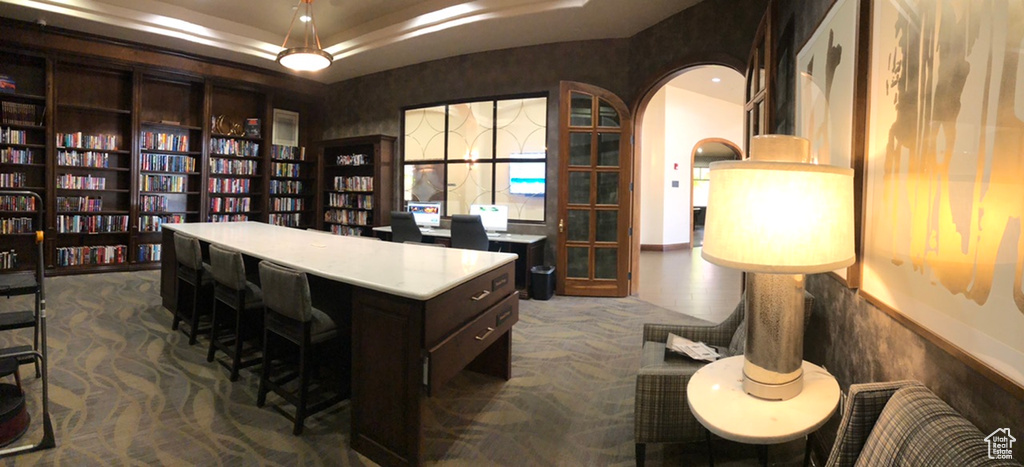 Office space with a tray ceiling and carpet floors