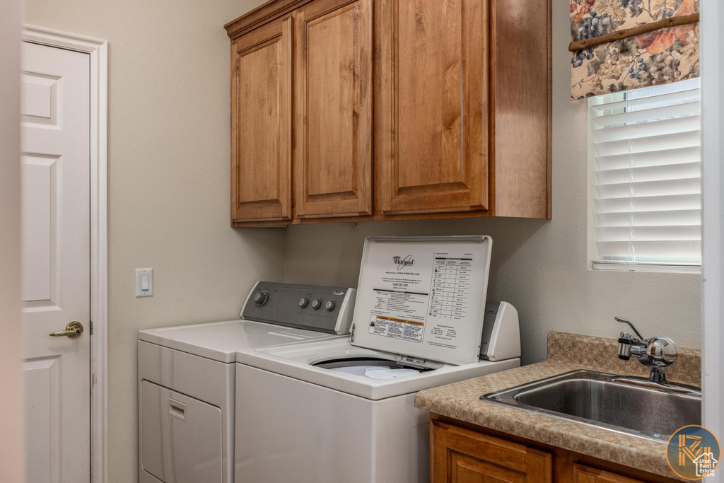 Clothes washing area featuring cabinets, sink, and independent washer and dryer