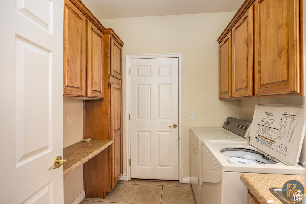 Washroom featuring independent washer and dryer, light tile floors, and cabinets