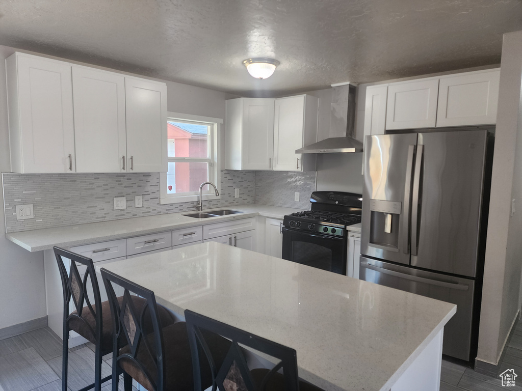 Kitchen with gas stove, wall chimney range hood, sink, white cabinets, and stainless steel fridge with ice dispenser