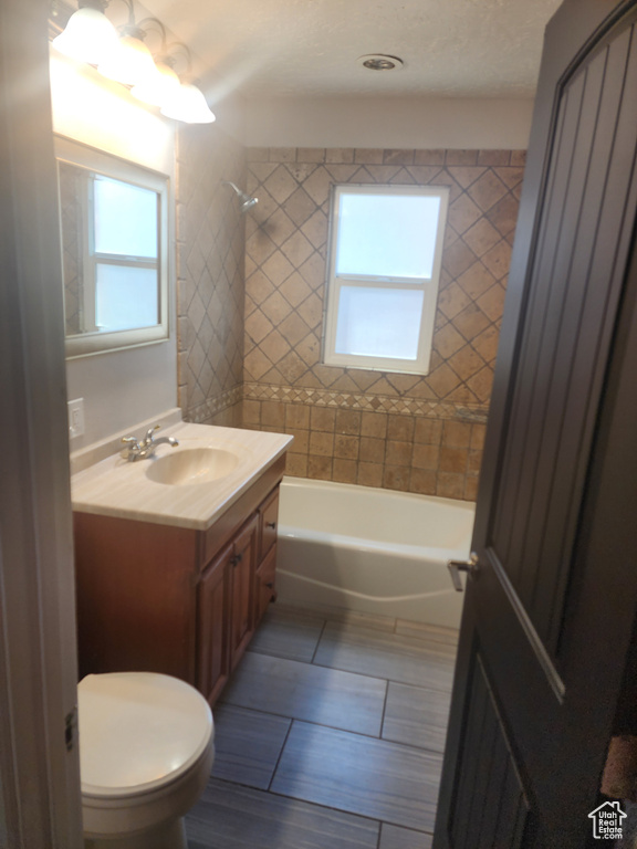 Full bathroom featuring tiled shower / bath combo, a wealth of natural light, toilet, and vanity