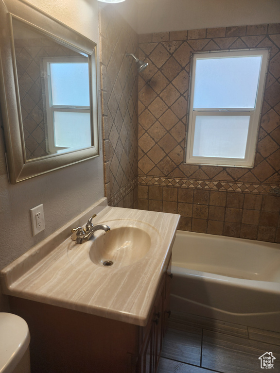 Full bathroom featuring tiled shower / bath, toilet, and vanity with extensive cabinet space