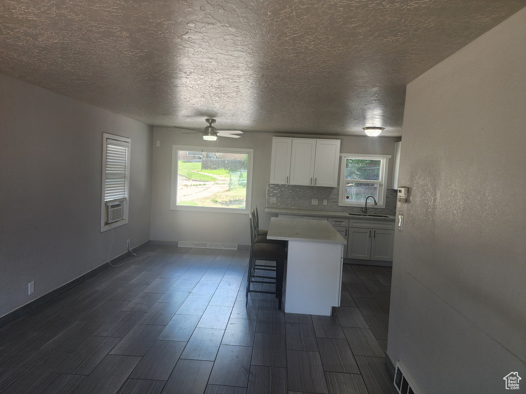 Kitchen with a kitchen island, sink, white cabinets, and backsplash