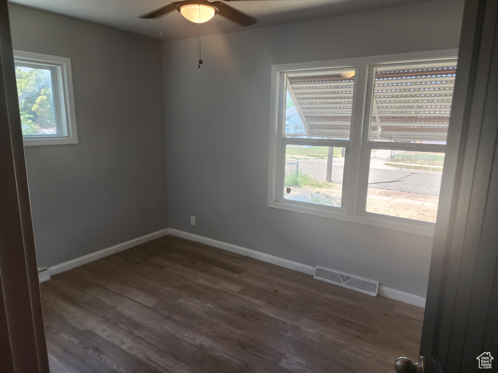 Spare room with dark wood-type flooring, plenty of natural light, and ceiling fan