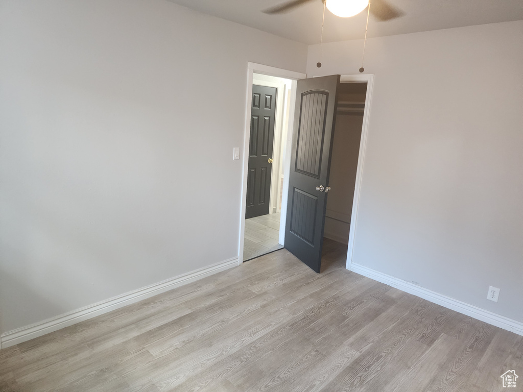 Empty room with ceiling fan and light hardwood / wood-style floors