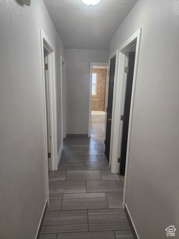 Hallway with a textured ceiling and dark tile floors