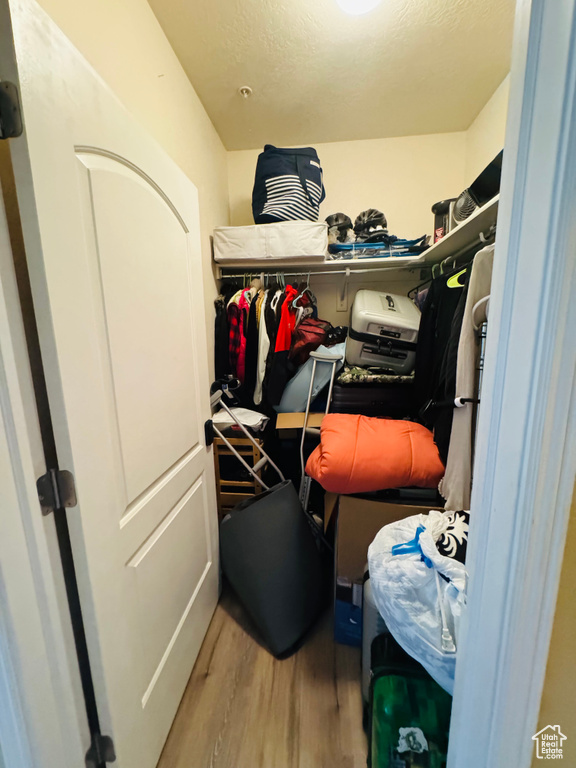 Walk in closet with hardwood / wood-style flooring