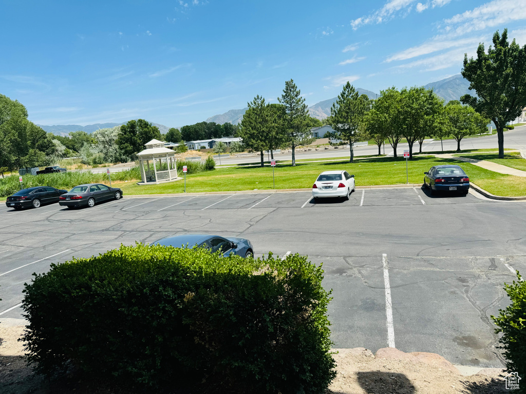 View of car parking featuring a mountain view and a lawn