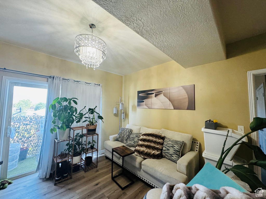 Living room with a chandelier, hardwood / wood-style flooring, and a textured ceiling