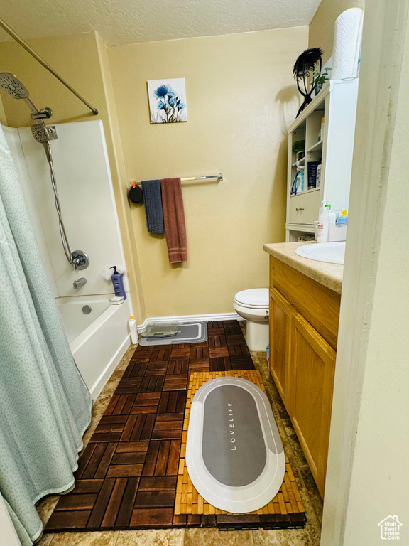 Full bathroom featuring shower / bath combo, a textured ceiling, parquet flooring, toilet, and vanity