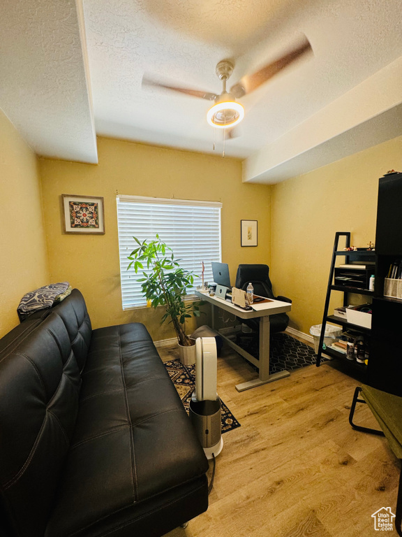 Living room featuring ceiling fan, hardwood / wood-style flooring, and a textured ceiling