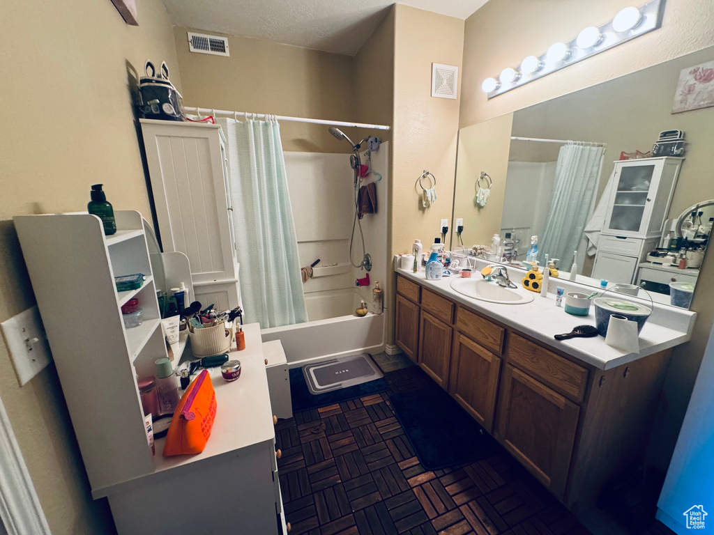 Bathroom with shower / bath combination with curtain, vanity, and a textured ceiling