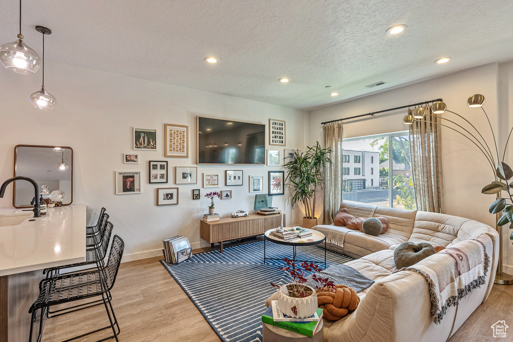 Living room with sink, light wood-type flooring, and a textured ceiling