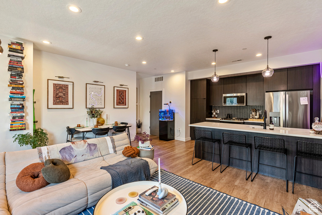 Living room featuring sink, a textured ceiling, and light hardwood / wood-style flooring