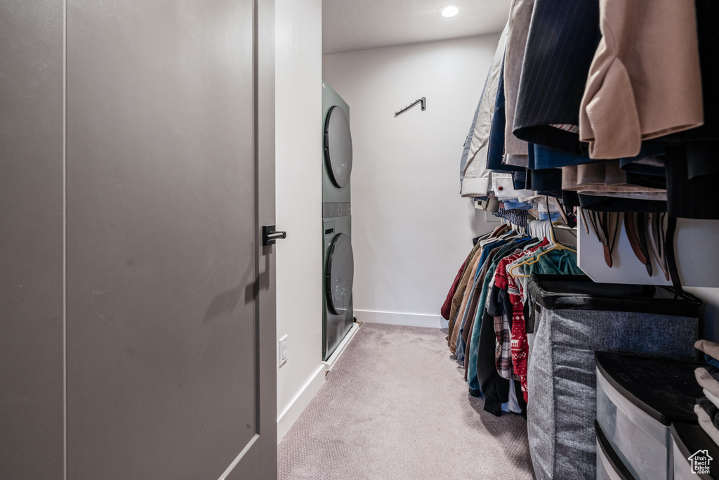 Walk in closet with light colored carpet and stacked washing maching and dryer