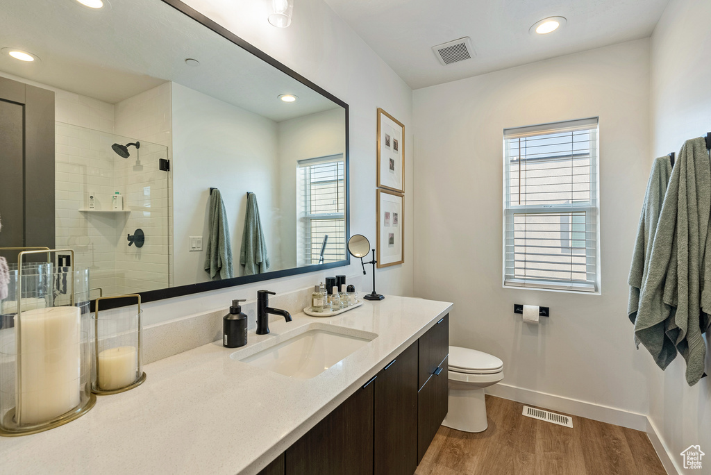 Bathroom featuring toilet, an enclosed shower, a healthy amount of sunlight, and hardwood / wood-style floors