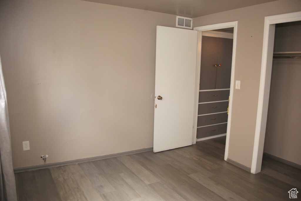 Unfurnished bedroom with a closet and hardwood / wood-style flooring