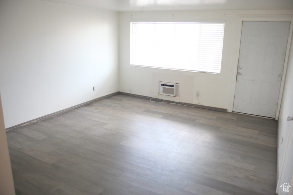 Unfurnished room featuring hardwood / wood-style flooring and an AC wall unit