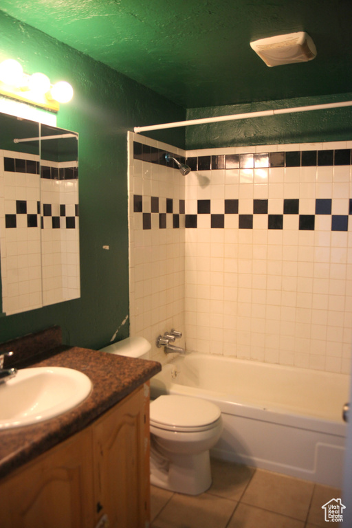 Full bathroom with tiled shower / bath combo, vanity, toilet, and tile floors