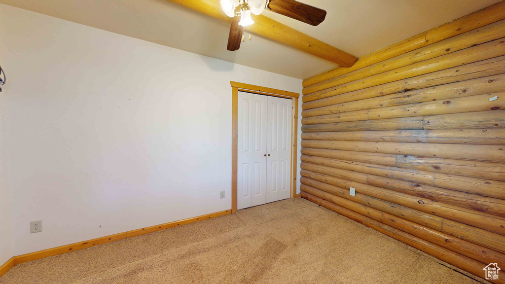Unfurnished room featuring ceiling fan, carpet flooring, and rustic walls