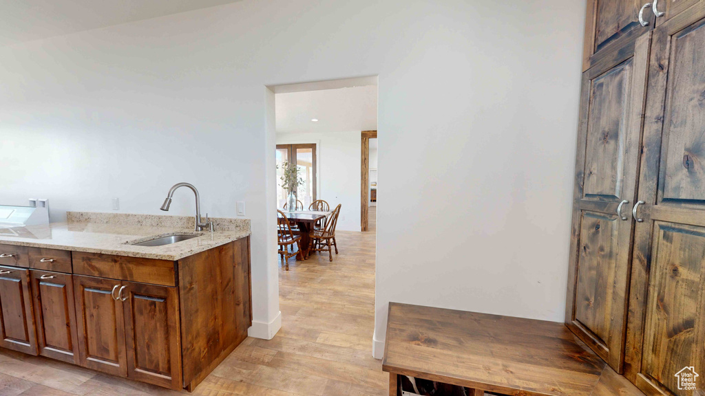 Kitchen with sink, light wood-type flooring, and light stone countertops