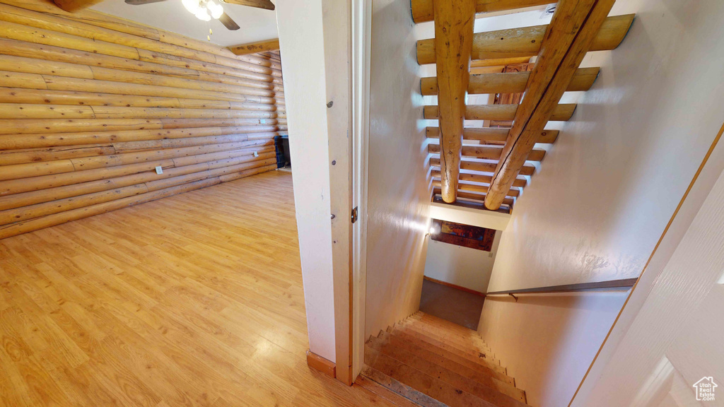 Stairs with ceiling fan, log walls, and light hardwood / wood-style flooring