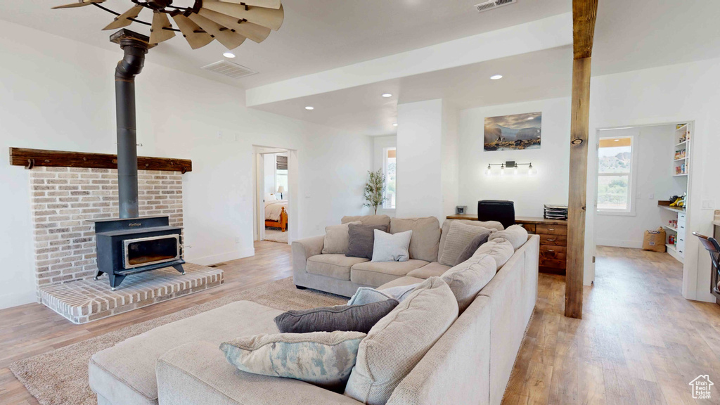 Living room featuring ceiling fan, a wood stove, and light hardwood / wood-style floors