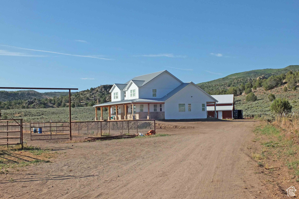 View of front of property featuring a mountain view, covered porch, and a rural view