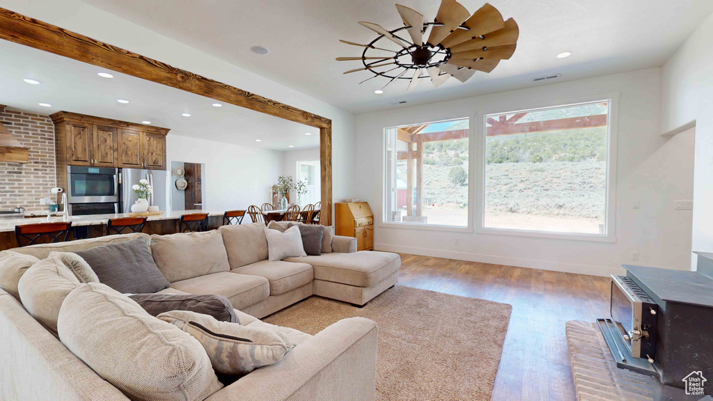 Living room featuring brick wall, plenty of natural light, ceiling fan, and hardwood / wood-style floors