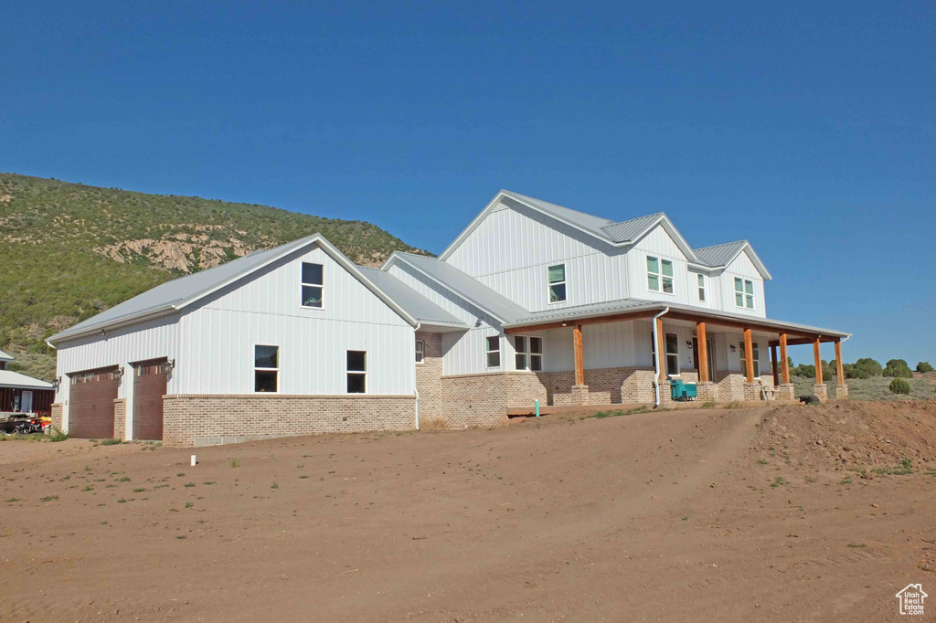 View of front of property with a garage, a mountain view, and covered porch