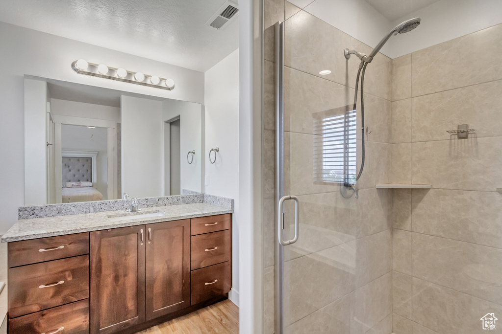 Bathroom with walk in shower, vanity, and hardwood / wood-style floors