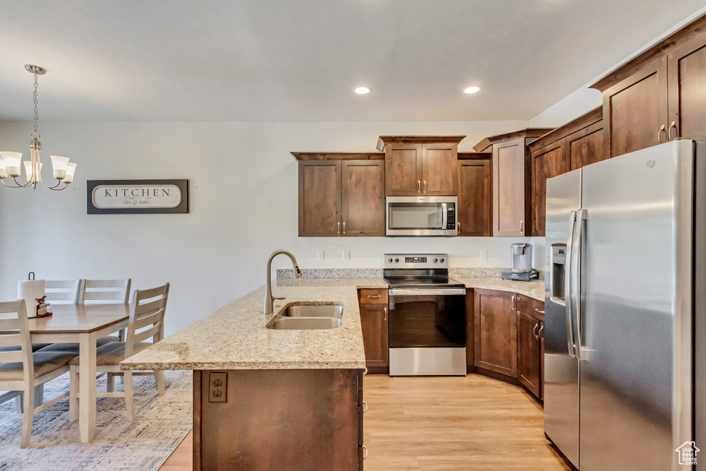 Kitchen with light hardwood / wood-style flooring, pendant lighting, a notable chandelier, sink, and appliances with stainless steel finishes