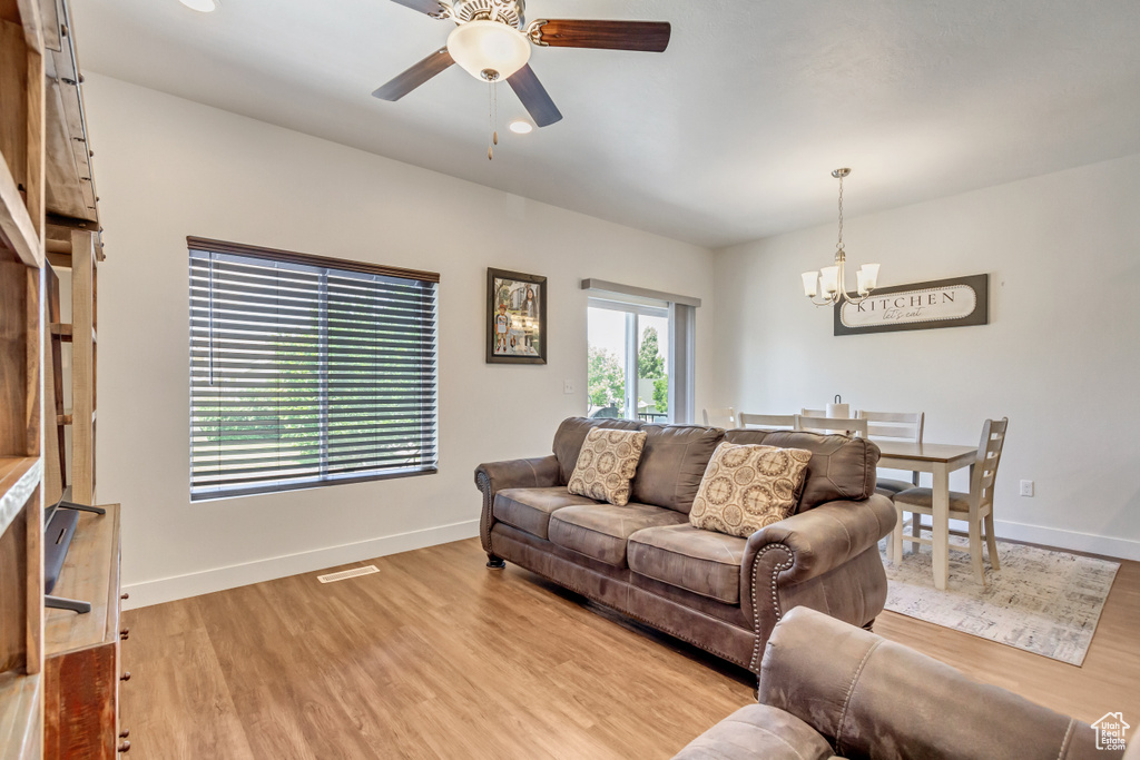 Living room with hardwood / wood-style flooring and ceiling fan with notable chandelier