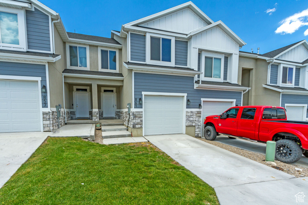 Multi unit property featuring a front yard and a garage