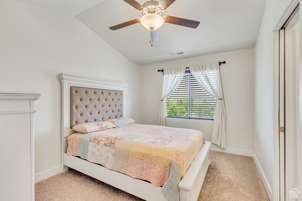 Carpeted bedroom with ceiling fan and lofted ceiling