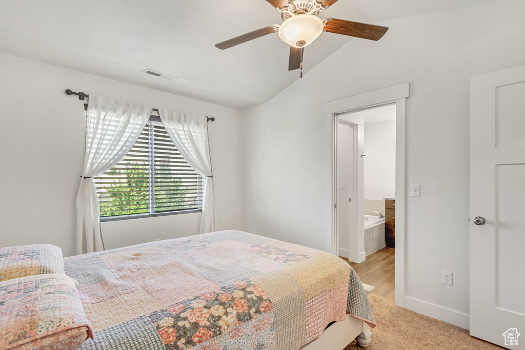 Bedroom with connected bathroom, ceiling fan, vaulted ceiling, and light colored carpet