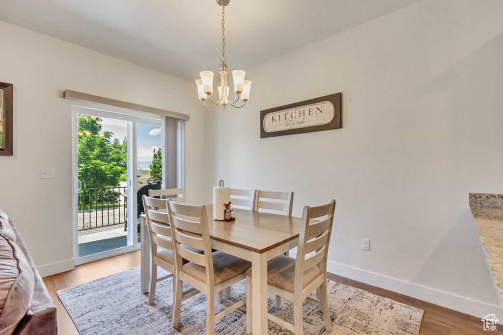 Dining space with light hardwood / wood-style floors, plenty of natural light, and a chandelier