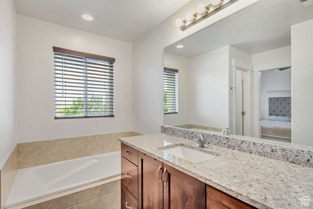 Bathroom featuring tiled tub and vanity