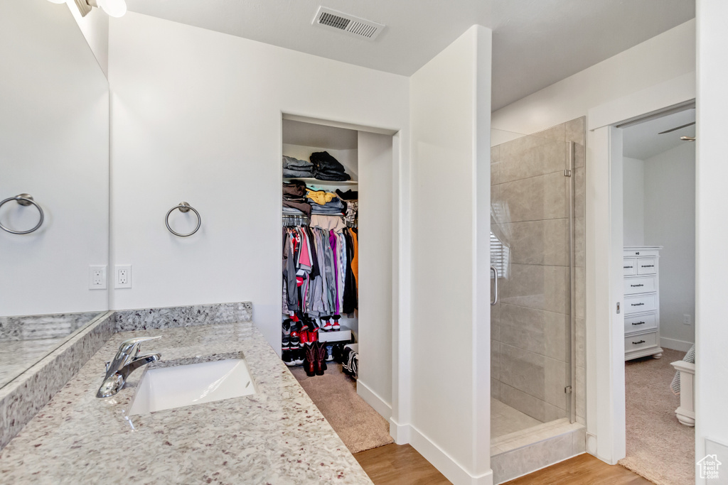 Bathroom with wood-type flooring, tiled shower, and vanity