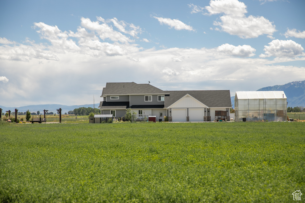 Rear view of property with a mountain view, an outdoor structure, and a lawn