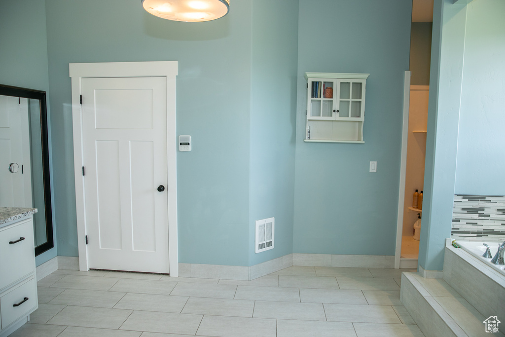 Bathroom featuring vanity, tiled bath, tile patterned floors, and tasteful backsplash