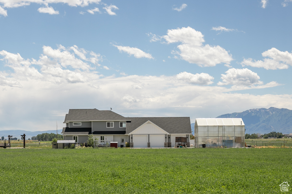 Exterior space featuring a mountain view, a garage, an outbuilding, and a lawn