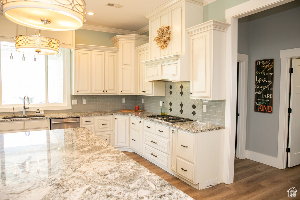 Kitchen featuring backsplash, stainless steel appliances, wood-type flooring, decorative light fixtures, and sink