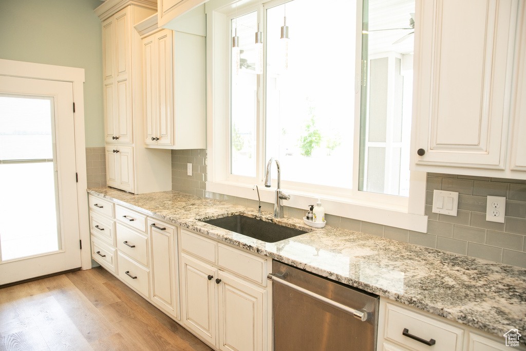 Kitchen with sink, decorative backsplash, dishwasher, and light hardwood / wood-style floors